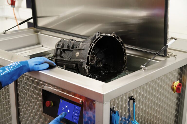 Person lowering a dirty machine part into an Ultrasonic washer for cleaning 